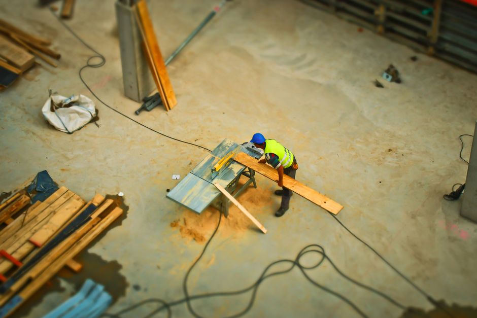 A professional cleaner from Carpet Cleaning W9 is operating a large, handheld floor cleaning machine in a residential room with a sloped ceiling. The room features a smooth, painted wall in a neutral,