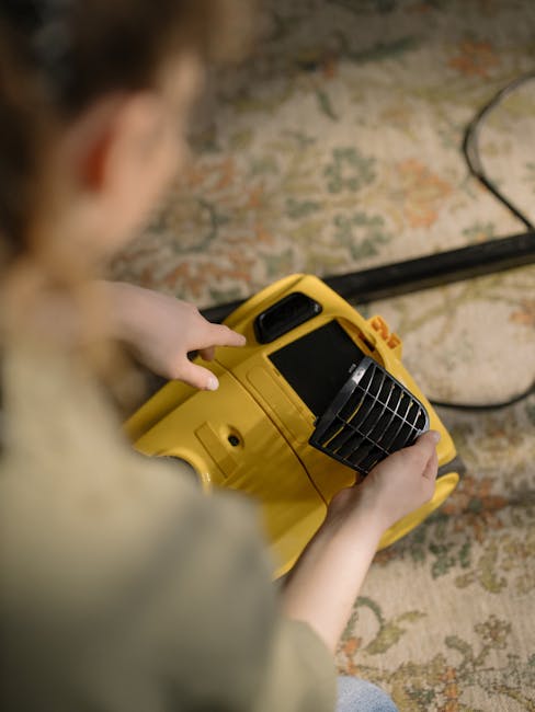 A professional cleaner dressed in white protective gear, including a hood, mask, gloves, and shoe covers, is performing deep cleaning on a beige carpet in a bright, modern living room. The cleaner is 